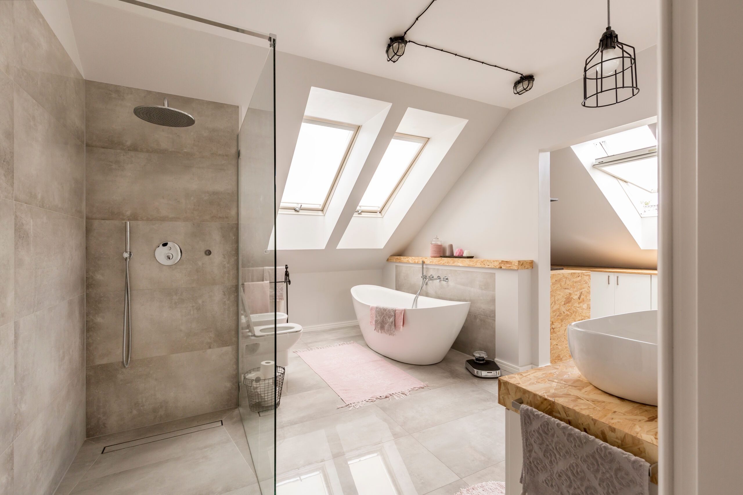 Modern bathroom interior with minimalistic shower and lighting, white toilet, sink, bathtub and roofwindows